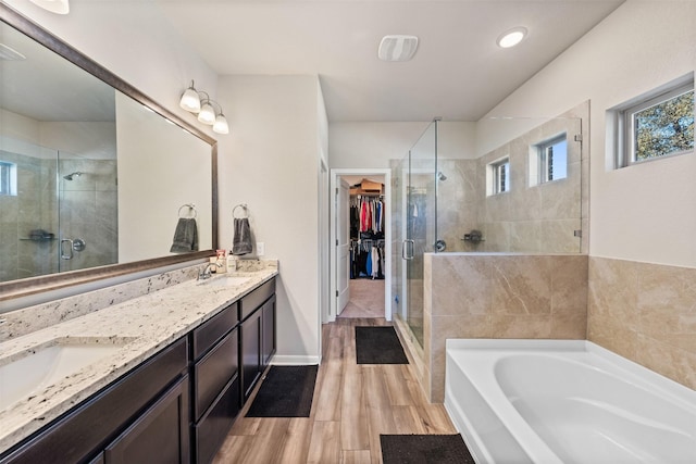 full bathroom with a walk in closet, double vanity, a sink, a shower stall, and a bath