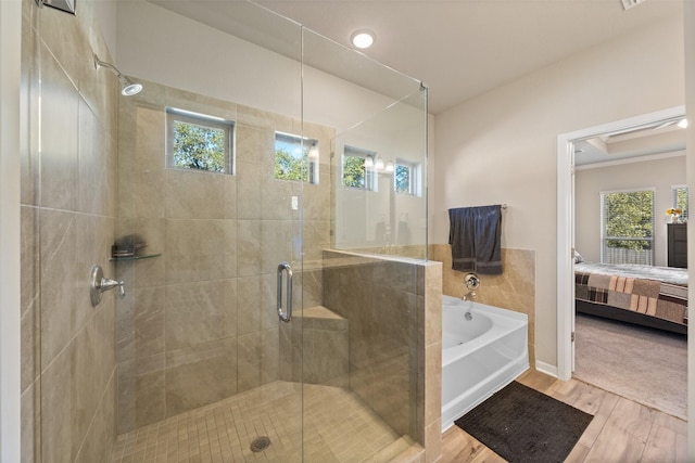 ensuite bathroom with ensuite bath, a garden tub, a shower stall, and wood finished floors