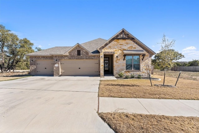 view of front of property with brick siding, an attached garage, fence, stone siding, and driveway