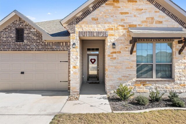 view of front of home with a shingled roof, concrete driveway, stone siding, an attached garage, and brick siding