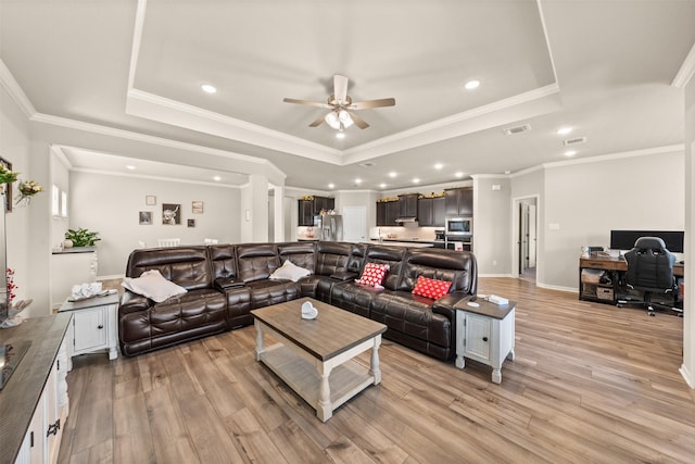 living room featuring a tray ceiling, visible vents, light wood-style flooring, and recessed lighting