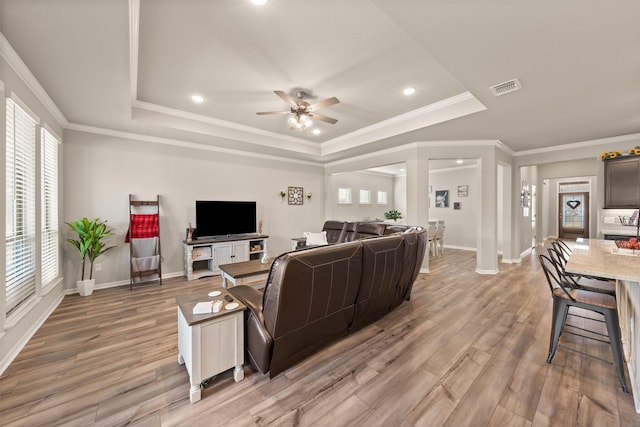 living room with light wood-type flooring, a tray ceiling, and visible vents