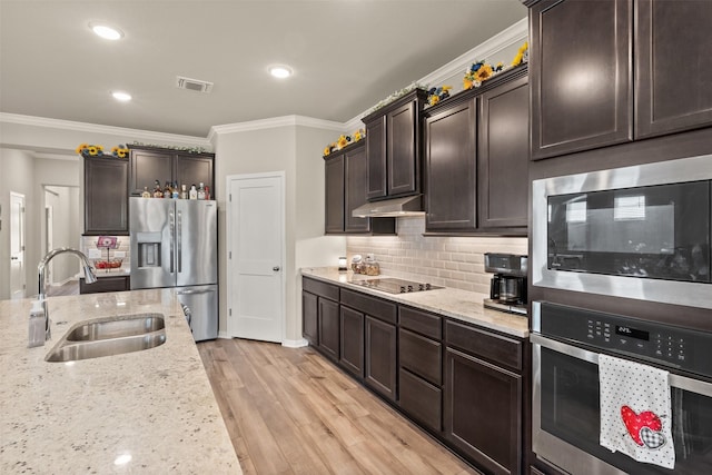 kitchen with under cabinet range hood, a sink, visible vents, appliances with stainless steel finishes, and light wood finished floors