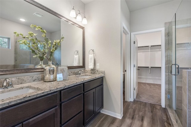 1207 Haley Ln, Salado, TX 76571 - bathroom with wood finished floors, double vanity, a shower stall, and a spacious closet