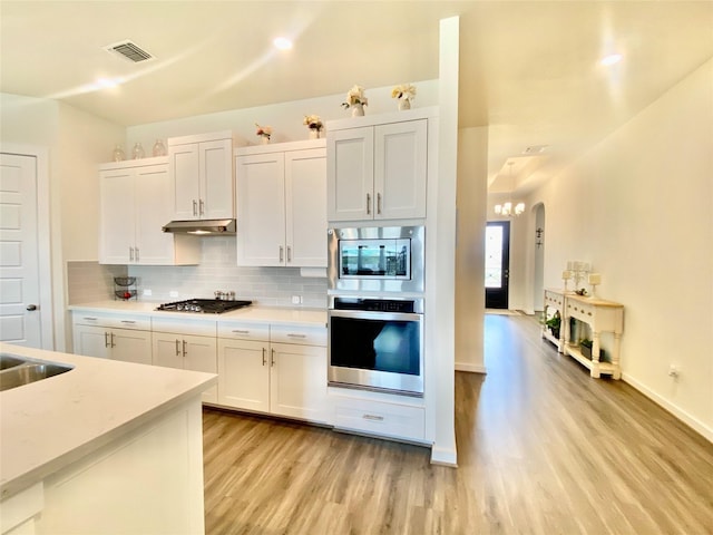 kitchen with decorative backsplash, white cabinetry, light hardwood / wood-style flooring, and stainless steel appliances