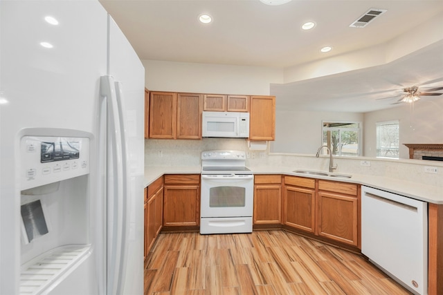 kitchen featuring ceiling fan, kitchen peninsula, sink, white appliances, and light wood-type flooring