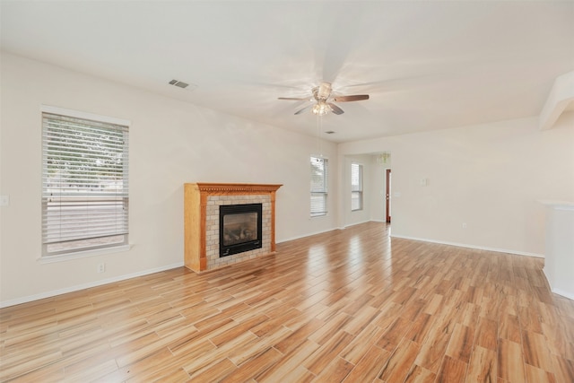 unfurnished living room featuring ceiling fan, light wood-type flooring, and a fireplace