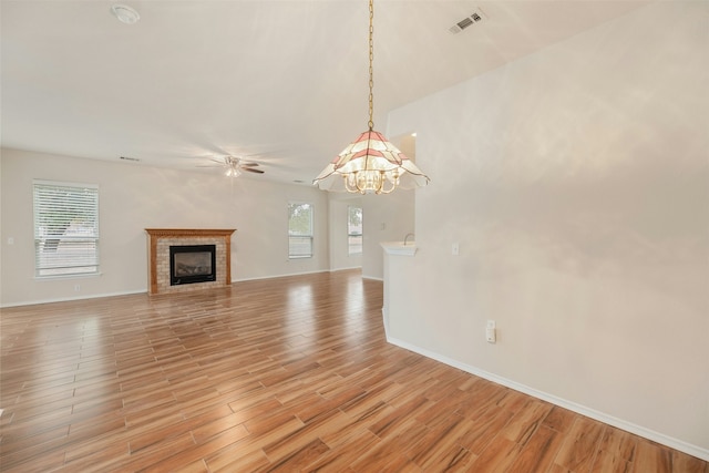 unfurnished living room featuring a healthy amount of sunlight, light wood-type flooring, and ceiling fan with notable chandelier