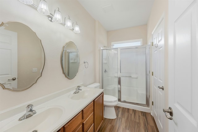 bathroom with toilet, wood-type flooring, a shower with door, and vanity