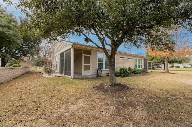 rear view of house featuring a sunroom and a yard