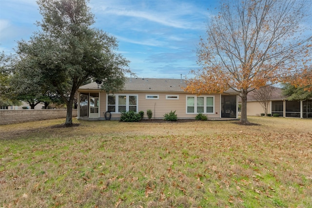 rear view of house featuring a sunroom and a yard