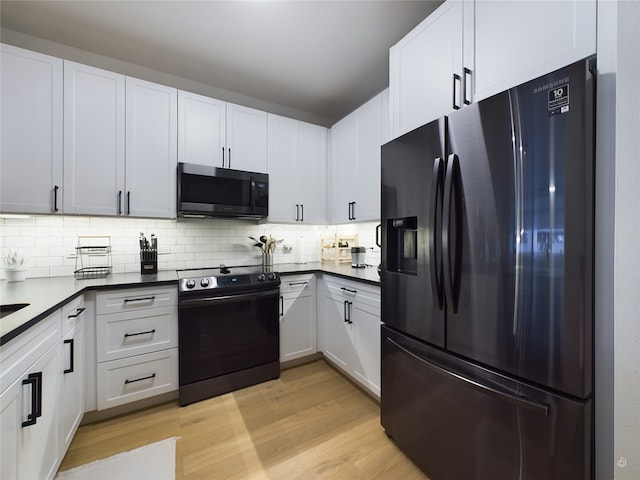 kitchen featuring black appliances, decorative backsplash, light wood-type flooring, and white cabinetry