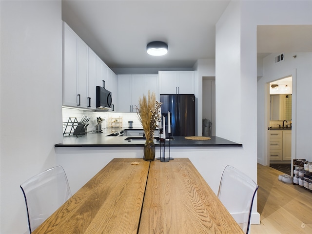 kitchen with decorative backsplash, sink, white cabinetry, light wood-type flooring, and stainless steel fridge with ice dispenser