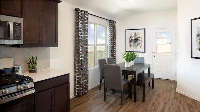 dining room with vaulted ceiling, plenty of natural light, and dark hardwood / wood-style floors