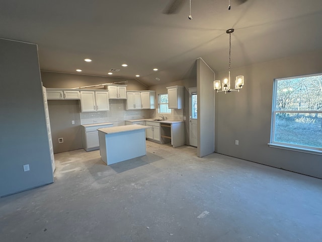 kitchen featuring white cabinets, vaulted ceiling, a wealth of natural light, and a kitchen island