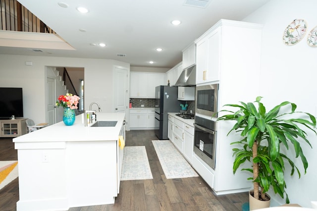 kitchen with white cabinets, decorative backsplash, sink, a kitchen island with sink, and stainless steel oven