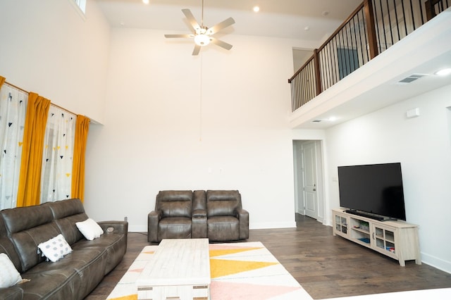 living room featuring ceiling fan, a towering ceiling, and dark hardwood / wood-style floors