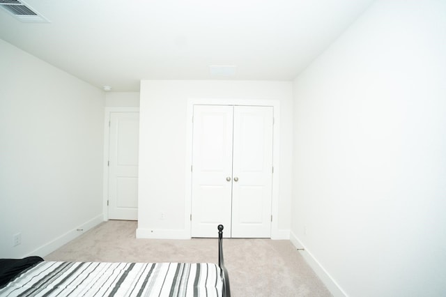 unfurnished bedroom with a closet and light colored carpet