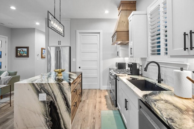 kitchen featuring light stone counters, white cabinetry, stainless steel appliances, and hanging light fixtures