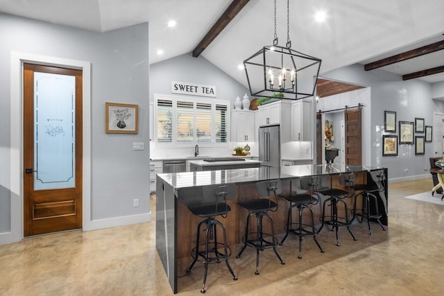 kitchen with a barn door, stainless steel appliances, white cabinetry, and a center island