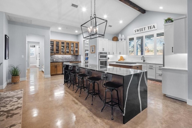 kitchen with tasteful backsplash, a breakfast bar, sink, a large island, and white cabinets