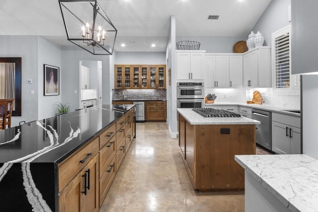 kitchen featuring a spacious island, white cabinets, appliances with stainless steel finishes, backsplash, and hanging light fixtures