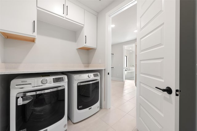 laundry room featuring light tile patterned floors, washer and dryer, and cabinets