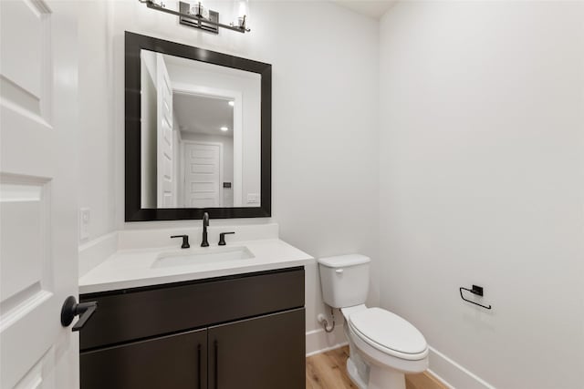 bathroom featuring wood-type flooring, toilet, and vanity