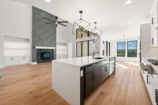 kitchen with white cabinetry, pendant lighting, an island with sink, and sink