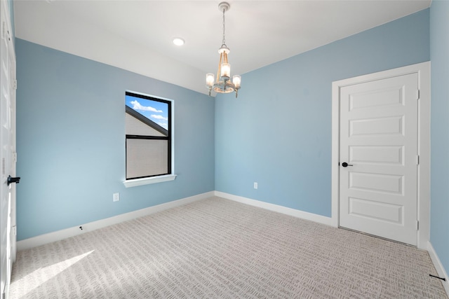 carpeted empty room with an inviting chandelier