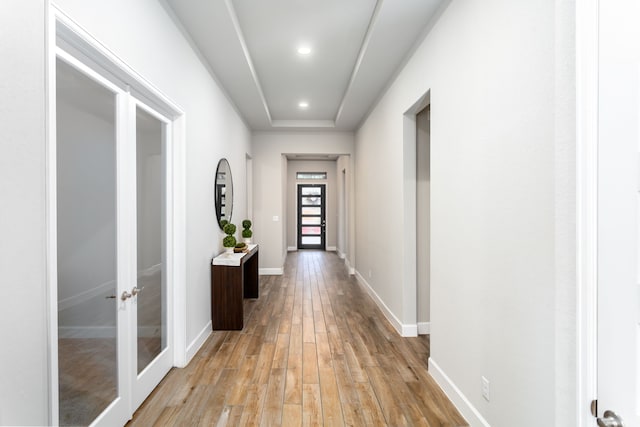 corridor with french doors, a raised ceiling, and light hardwood / wood-style flooring