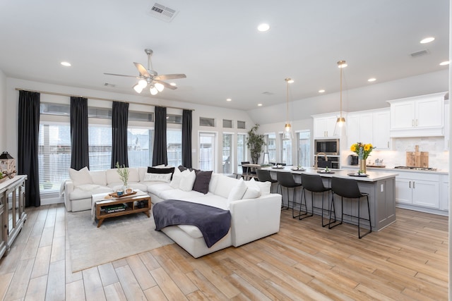 living room featuring light hardwood / wood-style floors, ceiling fan, and a healthy amount of sunlight