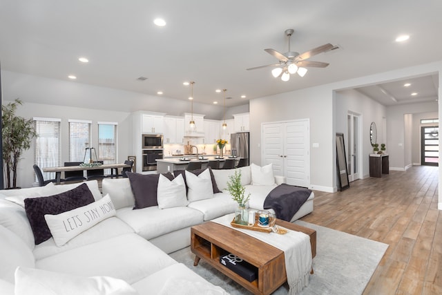 living room featuring ceiling fan, sink, a wealth of natural light, and light hardwood / wood-style flooring