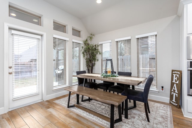 dining space with light wood-type flooring and lofted ceiling