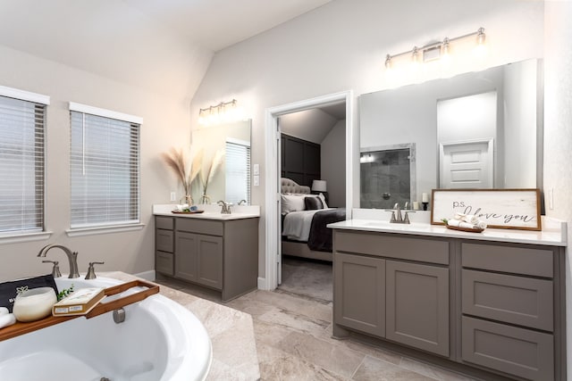 bathroom featuring tiled bath, vanity, and vaulted ceiling