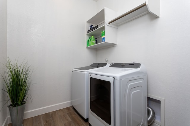 clothes washing area with washer and clothes dryer and dark hardwood / wood-style flooring