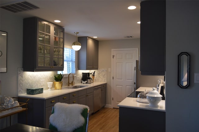 kitchen with gray cabinetry, light wood-type flooring, hanging light fixtures, stainless steel dishwasher, and sink