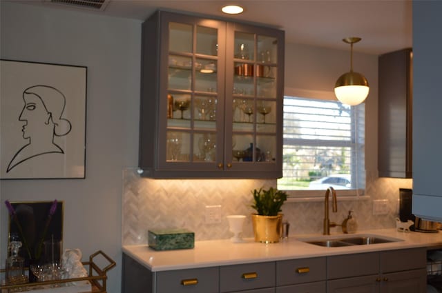 kitchen featuring gray cabinetry, backsplash, hanging light fixtures, and sink