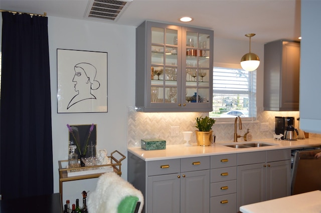 bar featuring tasteful backsplash, pendant lighting, sink, gray cabinetry, and dishwashing machine