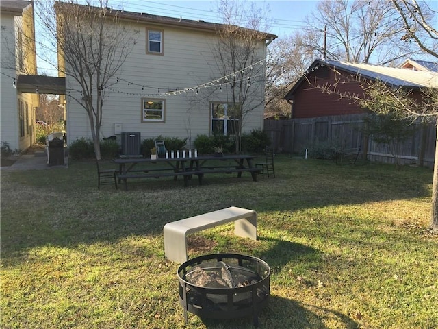 back of house with a lawn, an outdoor fire pit, and central air condition unit