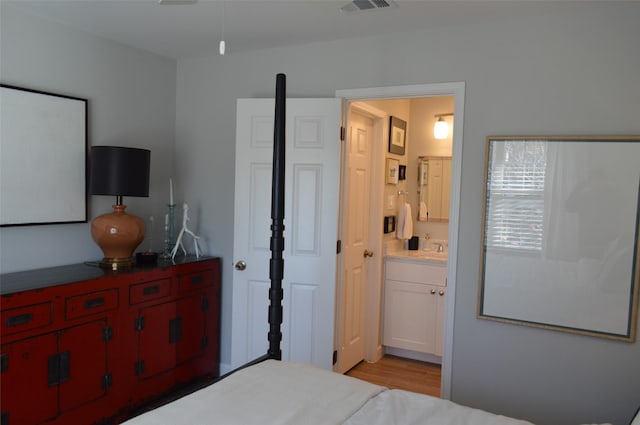 bedroom featuring connected bathroom and light wood-type flooring