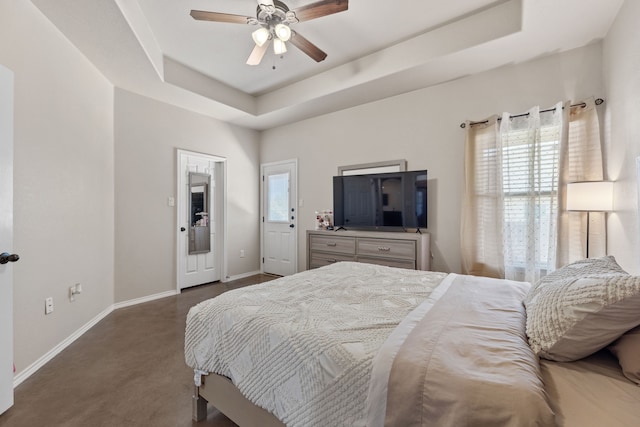 carpeted bedroom with ceiling fan and a tray ceiling