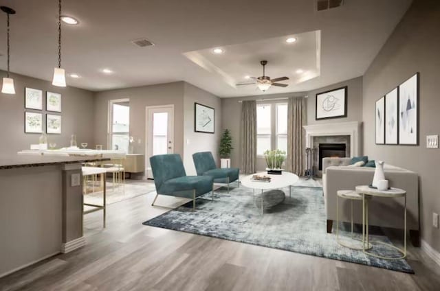 living room featuring ceiling fan, light hardwood / wood-style flooring, and a tray ceiling