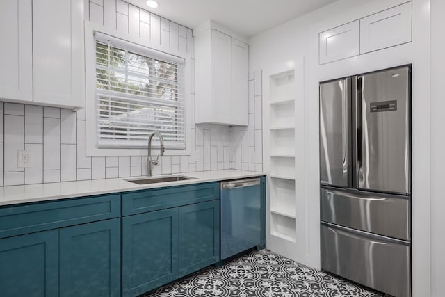 kitchen featuring backsplash, sink, appliances with stainless steel finishes, blue cabinetry, and white cabinets