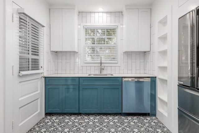 kitchen with sink, white cabinetry, blue cabinetry, and stainless steel appliances