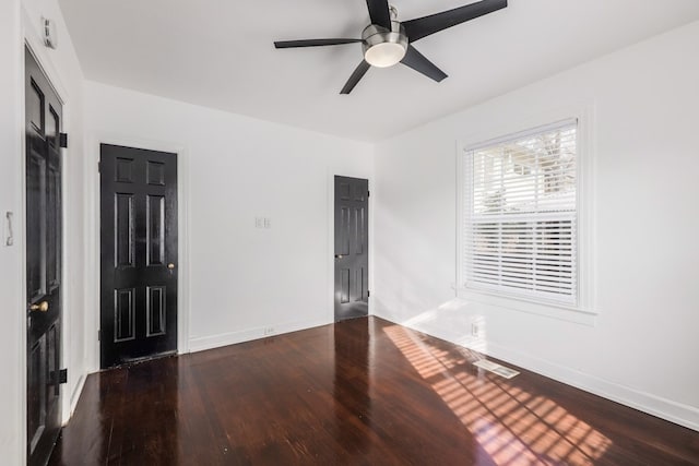 empty room with ceiling fan and dark hardwood / wood-style flooring