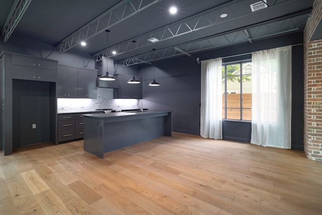 kitchen with light hardwood / wood-style flooring, decorative backsplash, sink, and pendant lighting