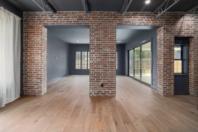 interior space with brick wall and light hardwood / wood-style flooring