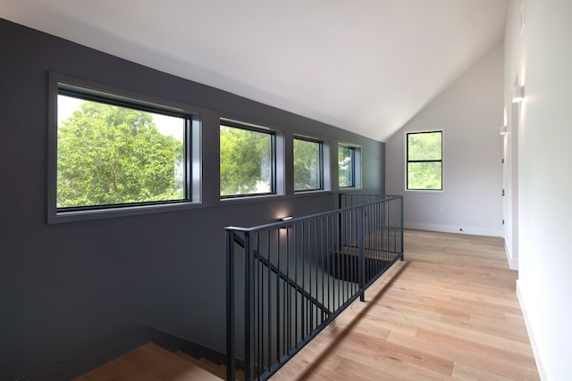 hallway with plenty of natural light, lofted ceiling, and light wood-type flooring