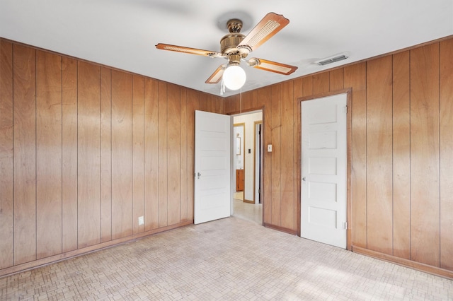 unfurnished bedroom with ceiling fan and wood walls